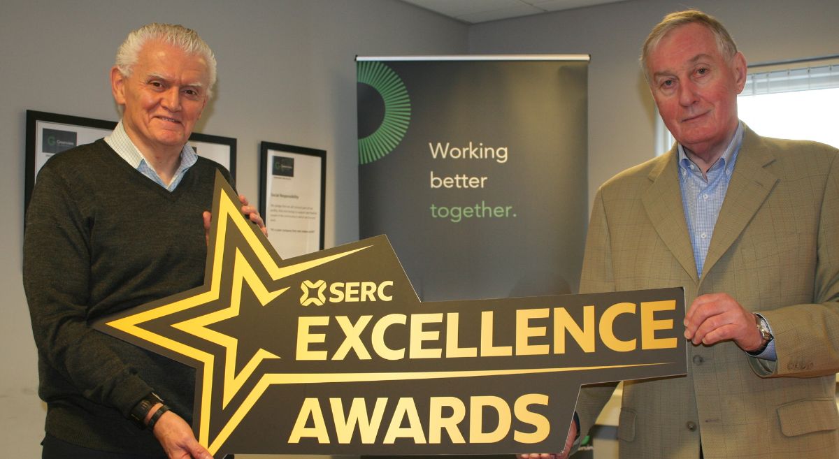 Two males holding a large star shaped cut out prop between them which says SERC Excellence Awards 